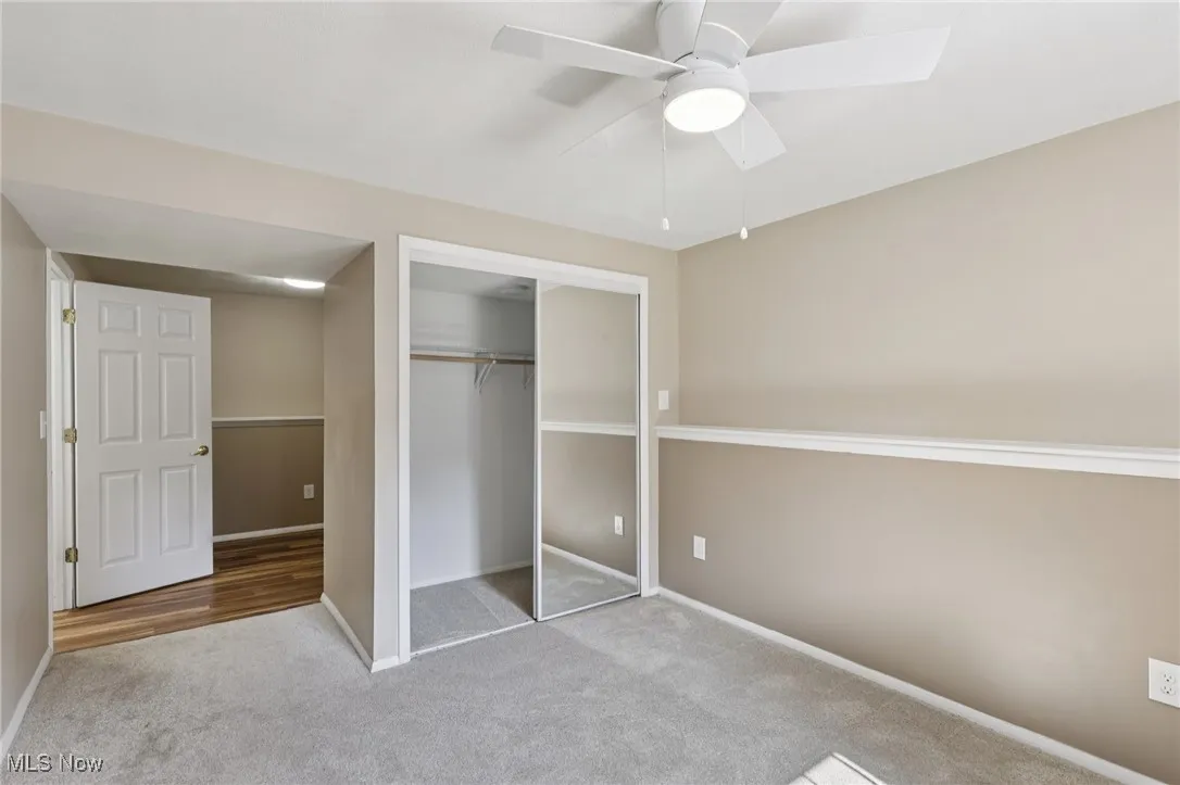 lower level third bedroom with lighted ceiling fan and window with custom blind