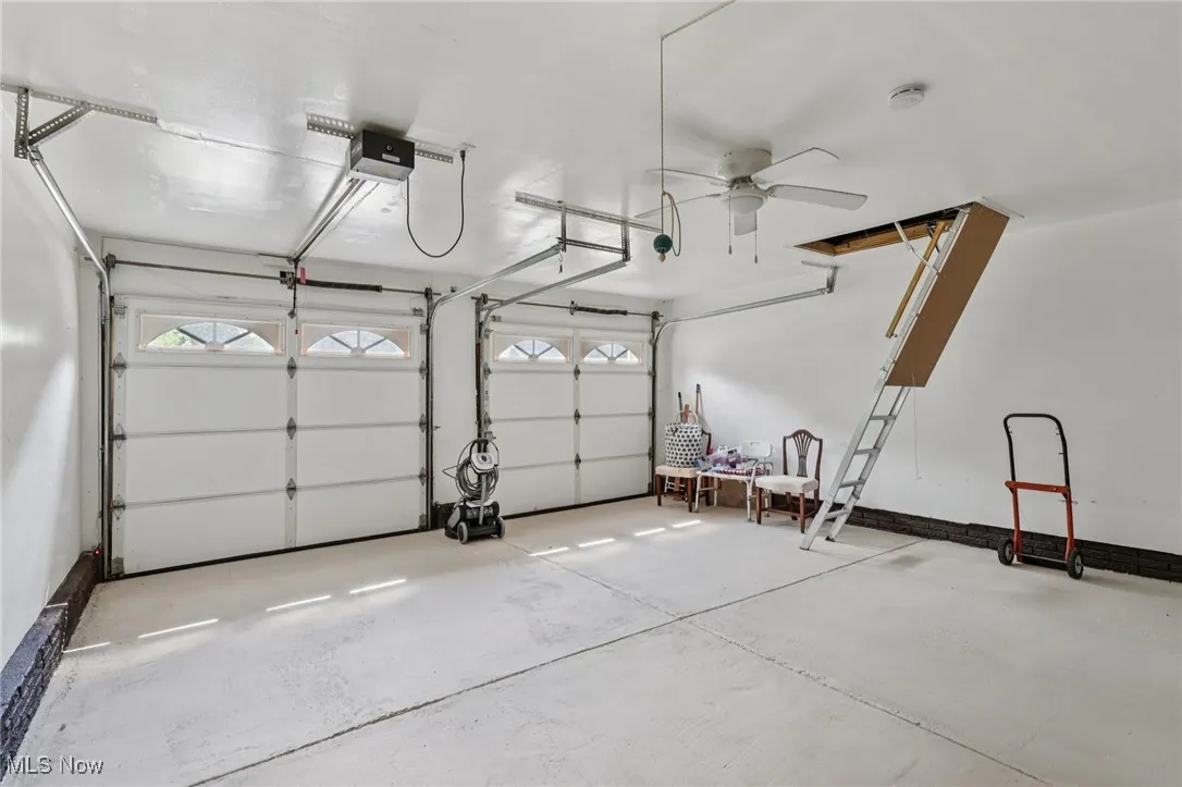 2 car garage with ceiling fan and stairs leading to attic with lighting and flooring for extra storage