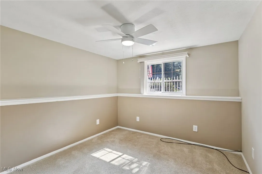lower level third bedroom with lighted ceiling fan and window with custom blind