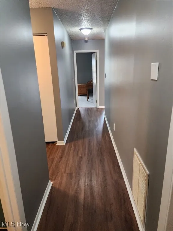 Hall with wood finished floors and a textured ceiling