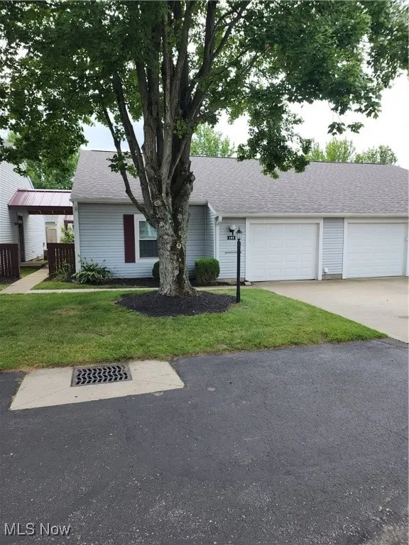 View of front of home featuring driveway, roof with shingles, and a front lawn