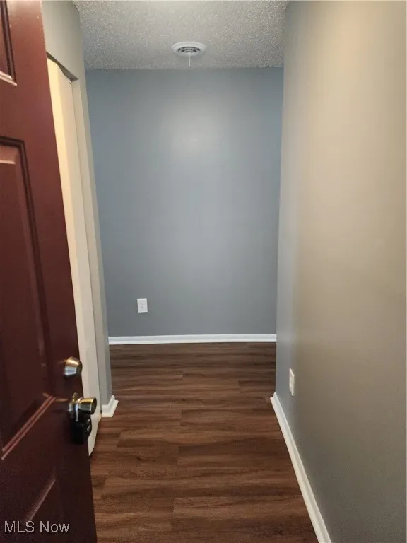 Hall with dark wood finished floors and a textured ceiling