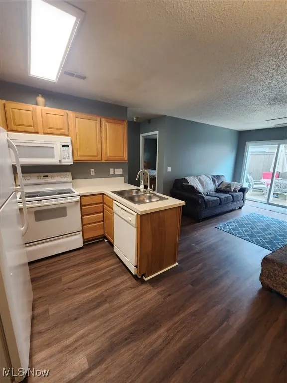Kitchen with stove, a peninsula, fridge, dark wood finished floors, and open floor plan