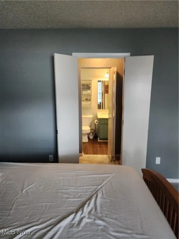Bedroom featuring wood finished floors and ensuite bath