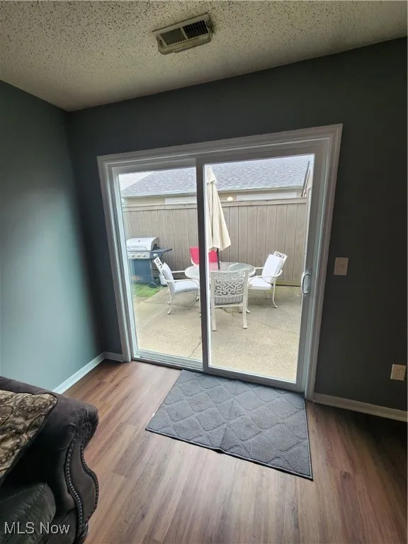 Doorway with wood finished floors and baseboards