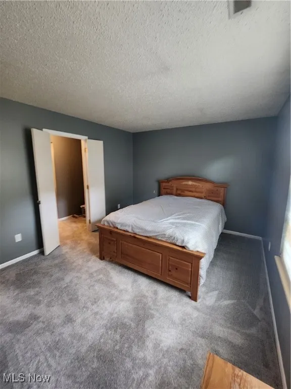 Bedroom with light colored carpet and a textured ceiling