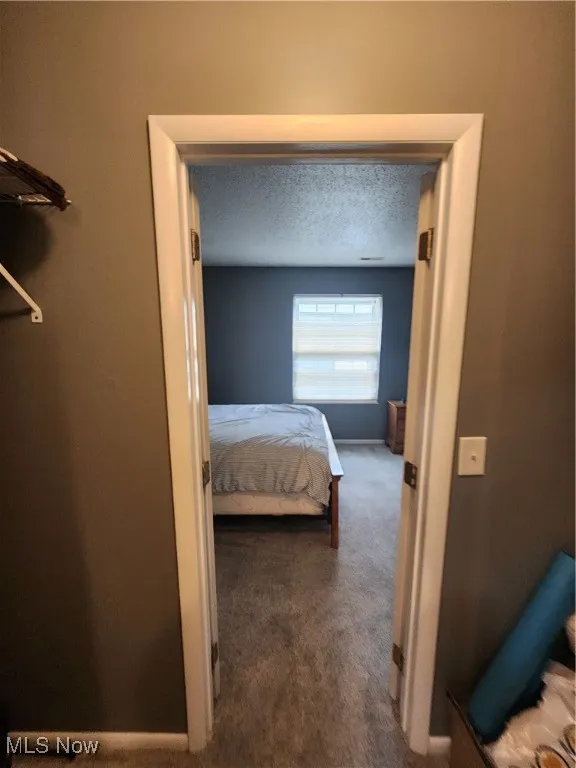 Carpeted bedroom with baseboards and a textured ceiling