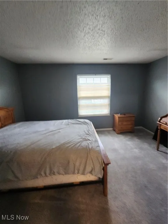 Bedroom with carpet and a textured ceiling