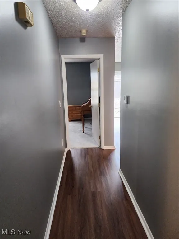 Hallway featuring dark wood-style floors and a textured ceiling