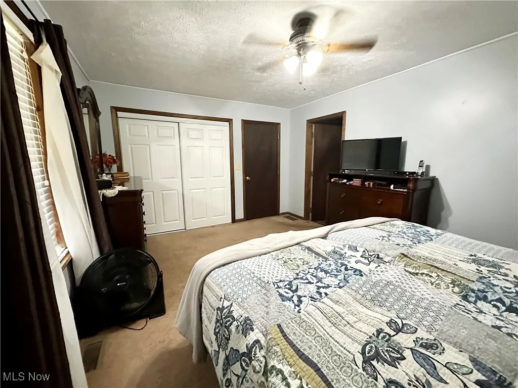 Master bedroom with ceiling fan and bathroom access.