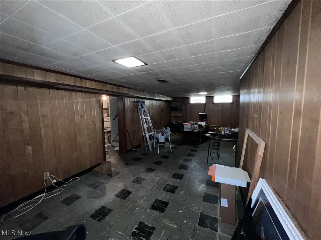 Below grade area featuring wood walls and tile patterned floors