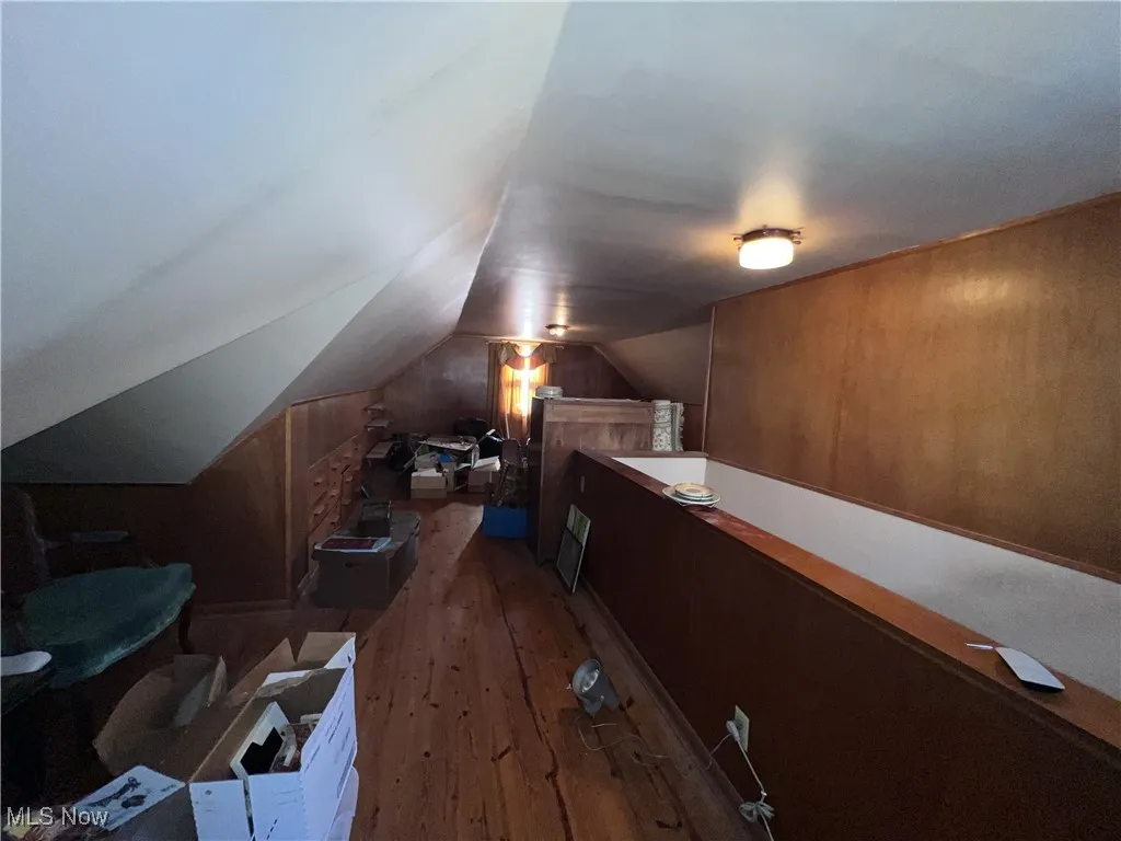 Additional living space featuring hardwood / wood-style floors, lofted ceiling, and wooden walls
