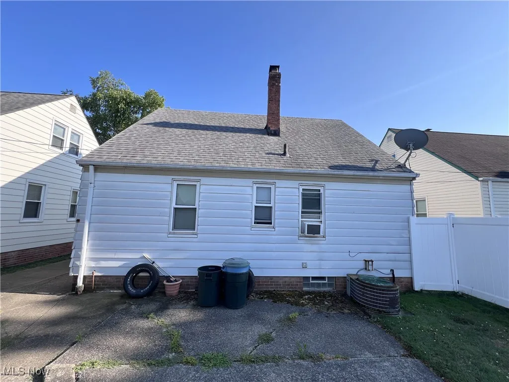 Back of house with roof with shingles and a chimney