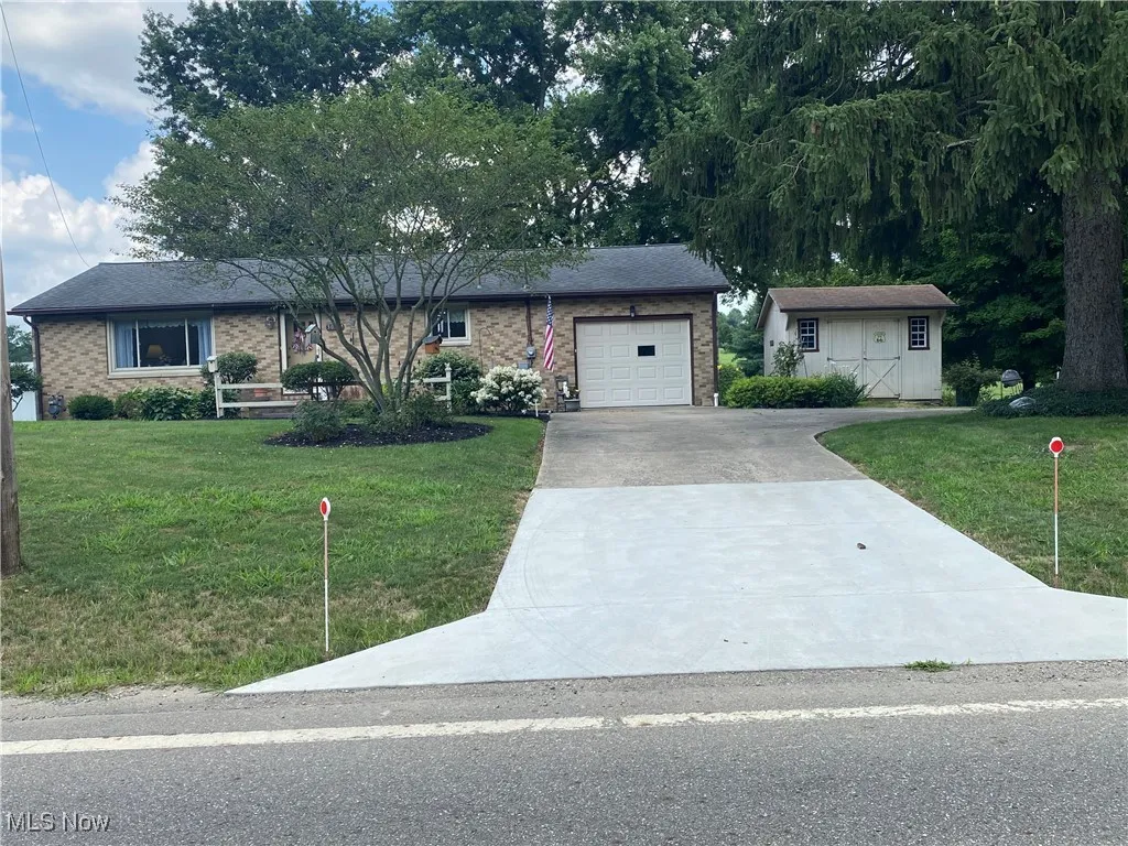 Ranch-style home with concrete driveway, a garage, brick siding, and a front yard