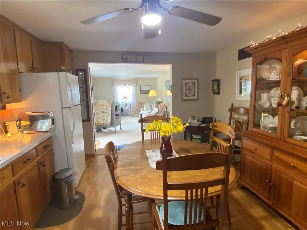Dining space with a ceiling fan and light wood-type flooring