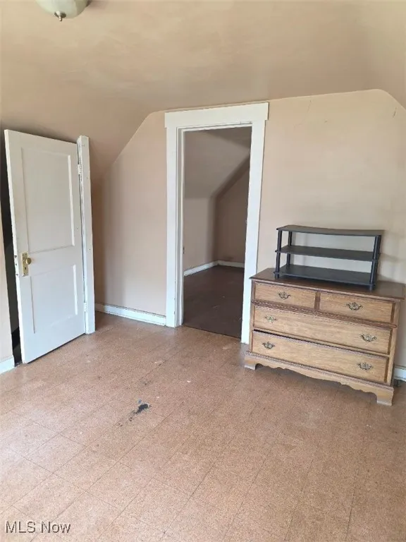 Additional living space featuring vaulted ceiling and baseboards
