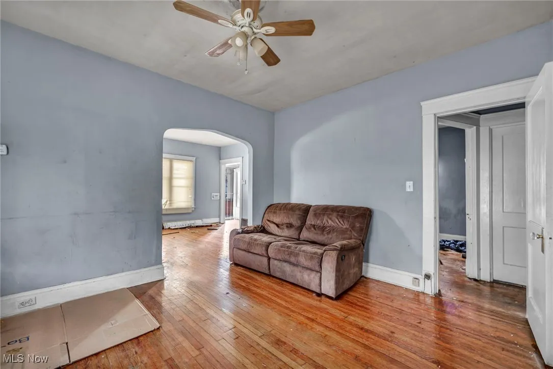 Living room with a ceiling fan, wood-type flooring, and arched walkways