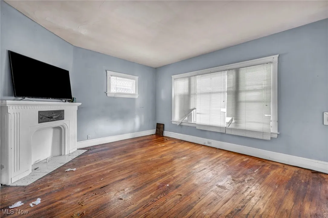 Unfurnished living room featuring wood-type flooring and a fireplace with flush hearth