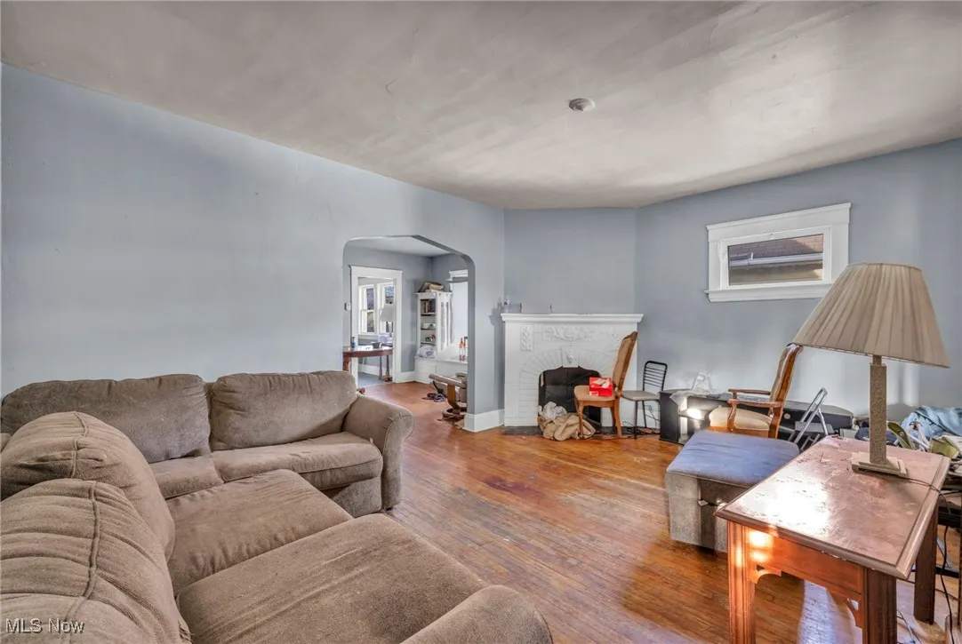 Living room with arched walkways, wood finished floors, and a fireplace