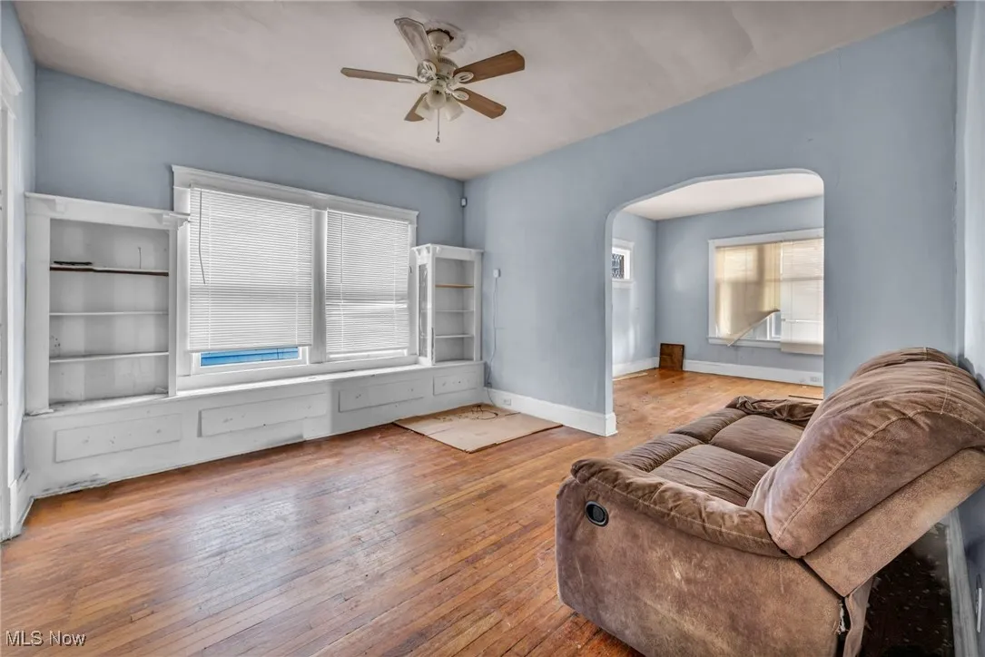 Living area featuring arched walkways, ceiling fan, and hardwood / wood-style flooring