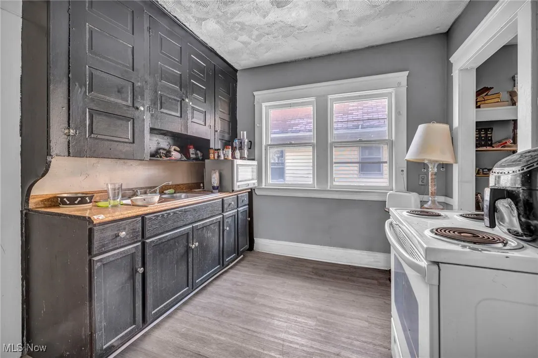 Kitchen featuring white range with electric cooktop, light wood-type flooring, and light countertops (2nd floor Unit)