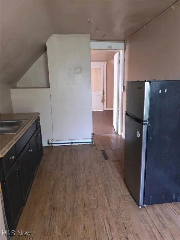 Kitchen featuring (3rd Floor)freestanding refrigerator, wood finished floors, dark cabinetry, and lofted ceiling