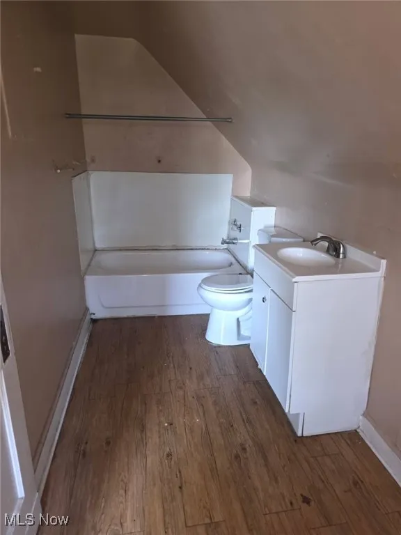 Bathroom featuring wood finished floors, vanity, and shower / tub combination