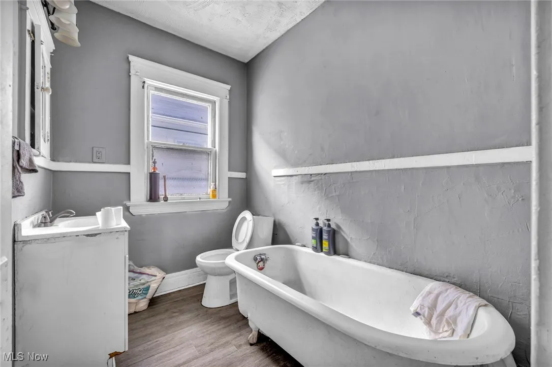Full bath with vanity, a freestanding tub, and wood finished floors