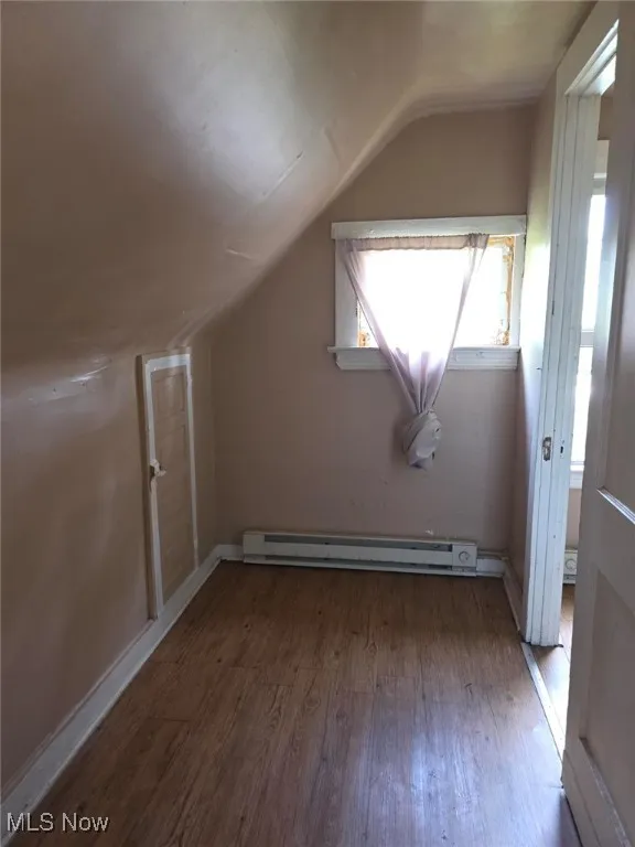 Bonus room with wood finished floors, vaulted ceiling, and a baseboard radiator