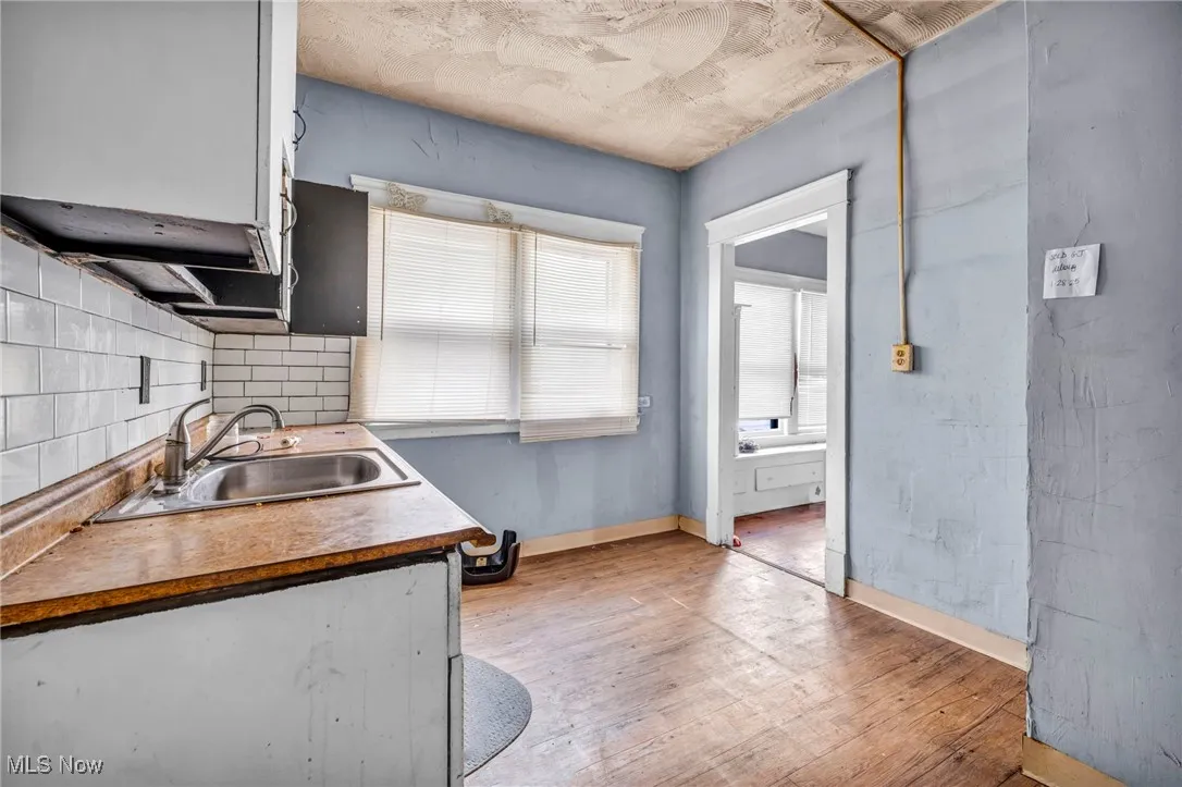 Kitchen featuring light wood-type flooring, decorative backsplash, and white cabinets (1st floor unit)