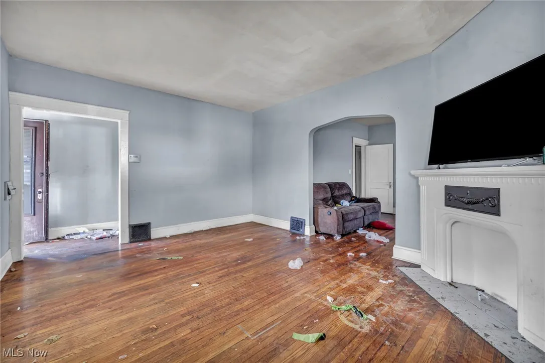Unfurnished living room featuring arched walkways and hardwood / wood-style floors