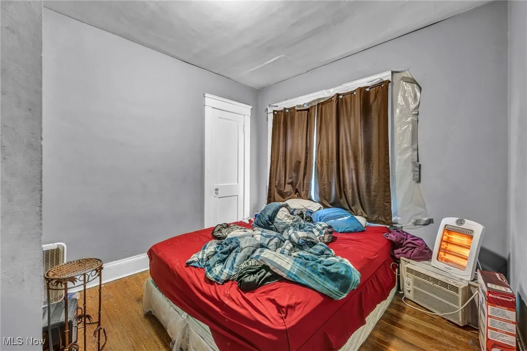 Bedroom with wood finished floors and a wall mounted air conditioner