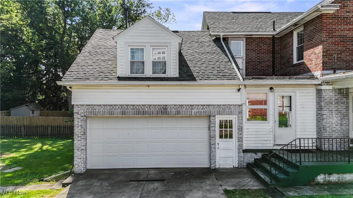 View of front of home featuring a garage, a shingled roof, concrete driveway, and brick siding