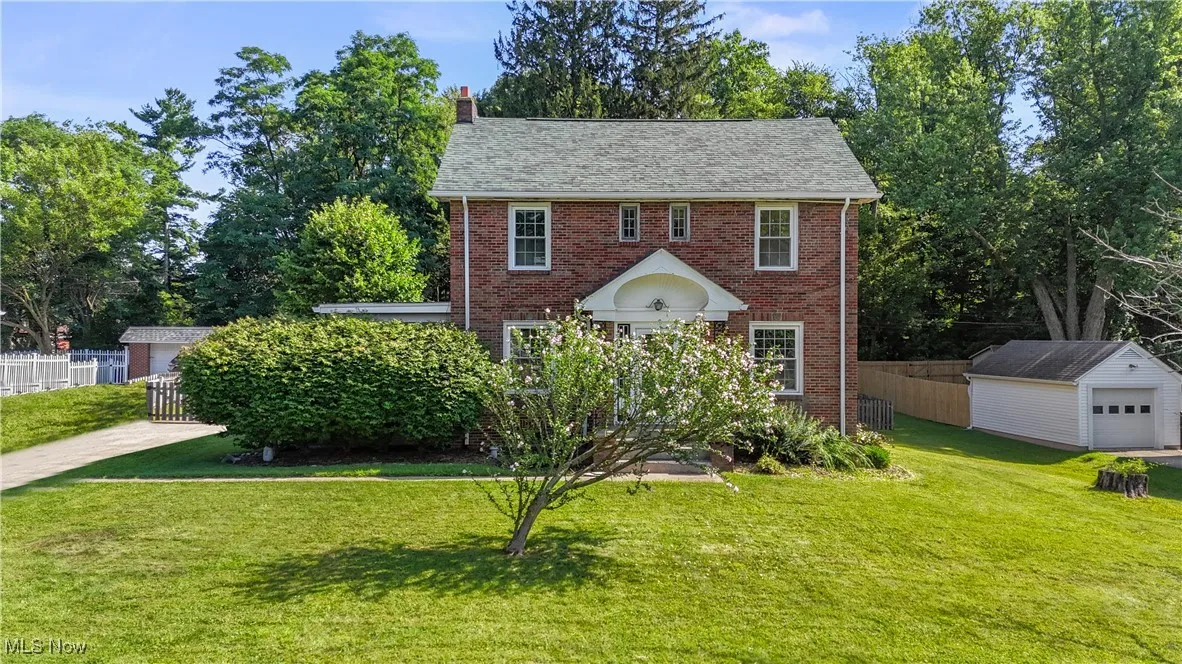 Colonial-style house featuring brick siding, an outbuilding, and a chimney
