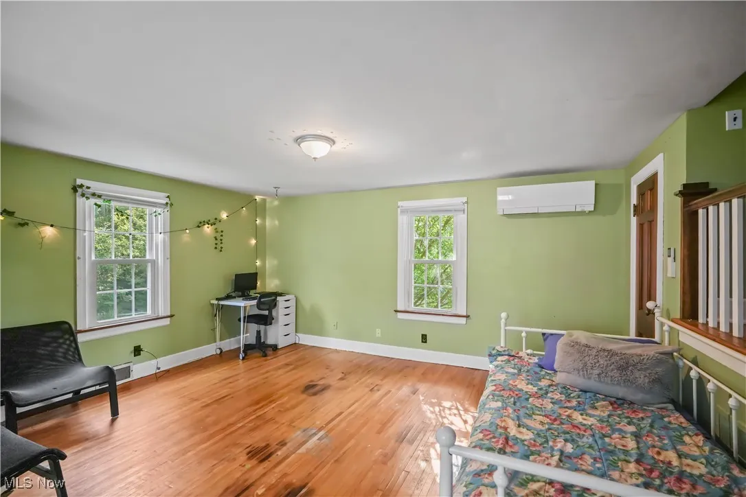 Living area with plenty of natural light, light wood-type flooring, a wall mounted AC, and an office area