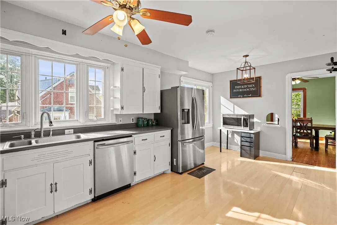 Kitchen featuring a ceiling fan, stainless steel appliances, light wood-type flooring, and white cabinets