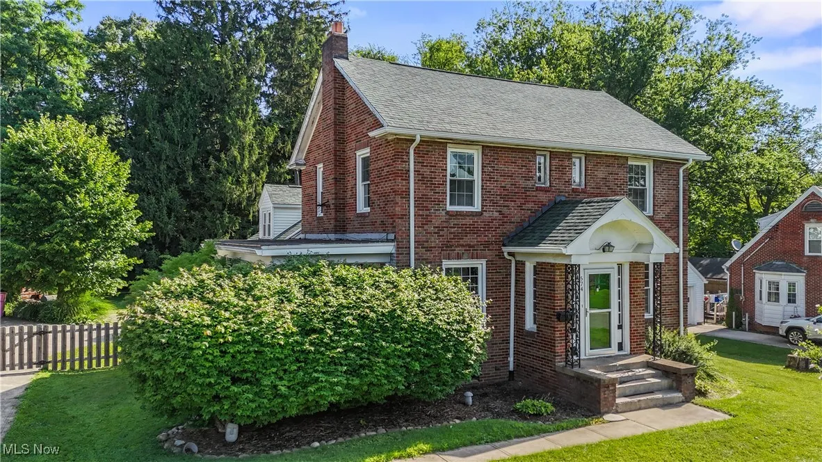 View of front of property featuring brick siding, a chimney, and roof with shingles