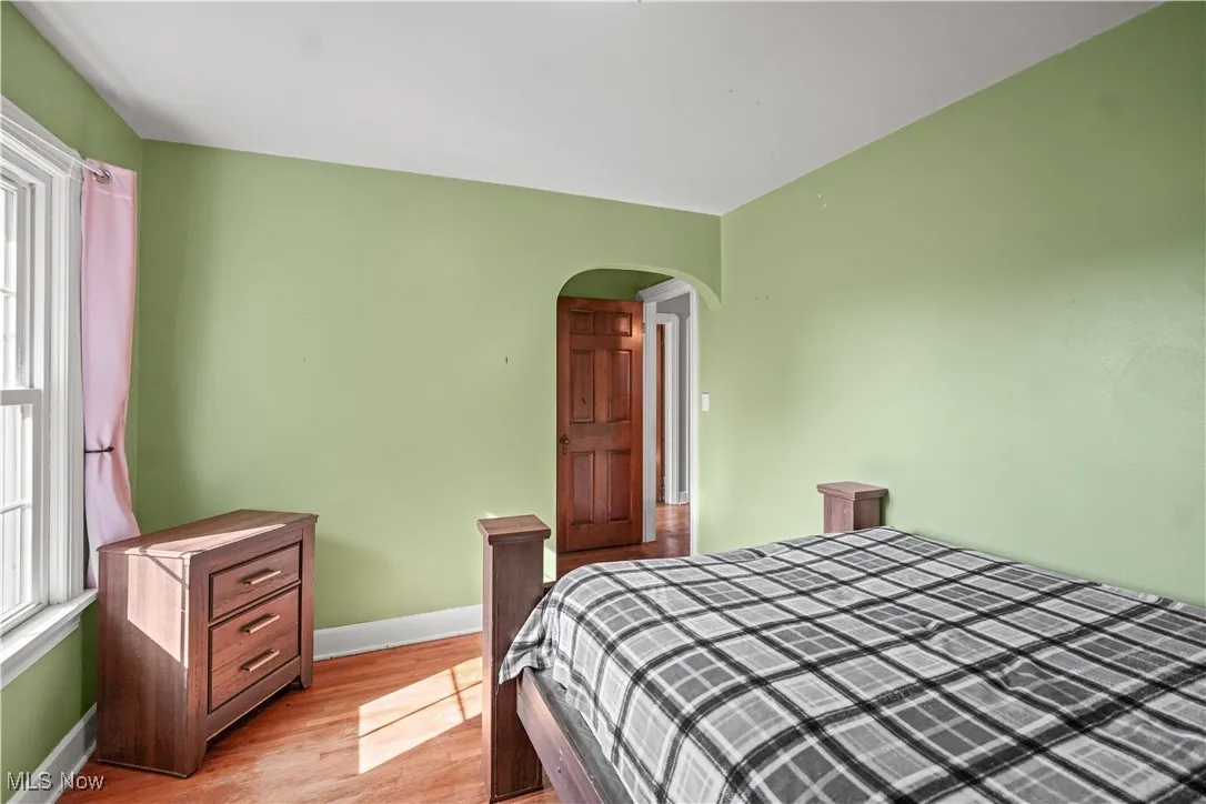 Bedroom with arched walkways and light wood-style flooring