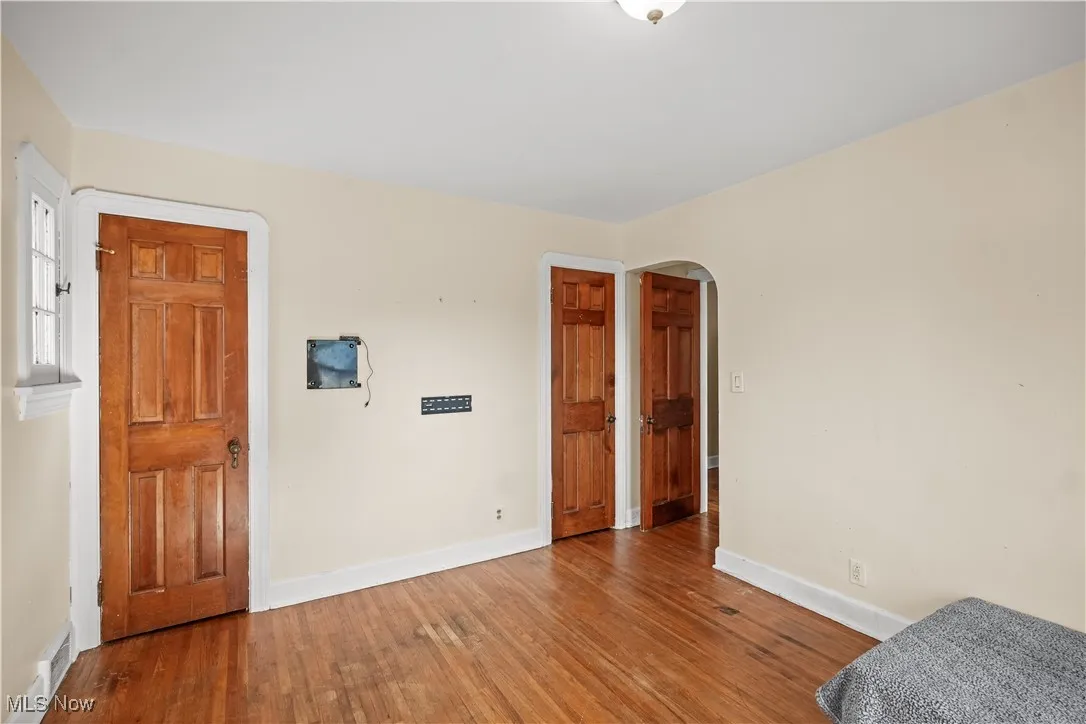 Unfurnished bedroom featuring arched walkways and wood finished floors