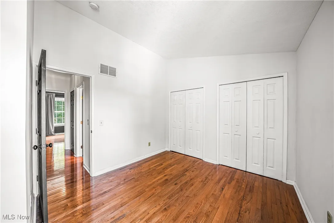 Guest Bedroom with Hardwood Flooring and Dual Closets