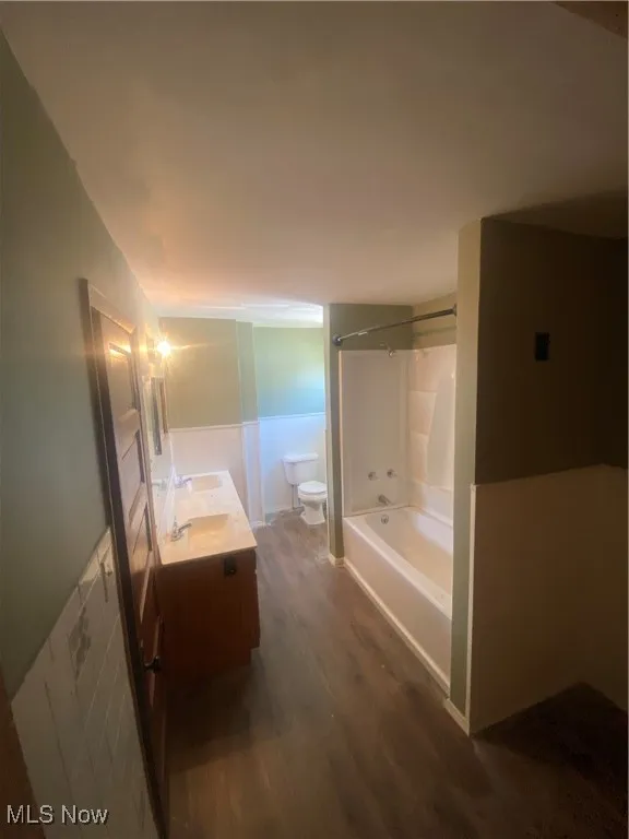 Full bath featuring wood finished floors, double vanity, and shower / bath combination