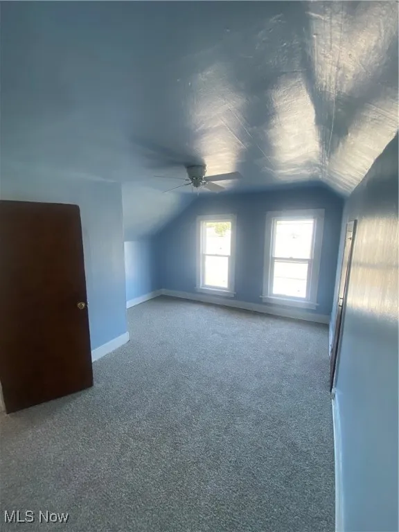 Additional living space with vaulted ceiling, carpet, and ceiling fan