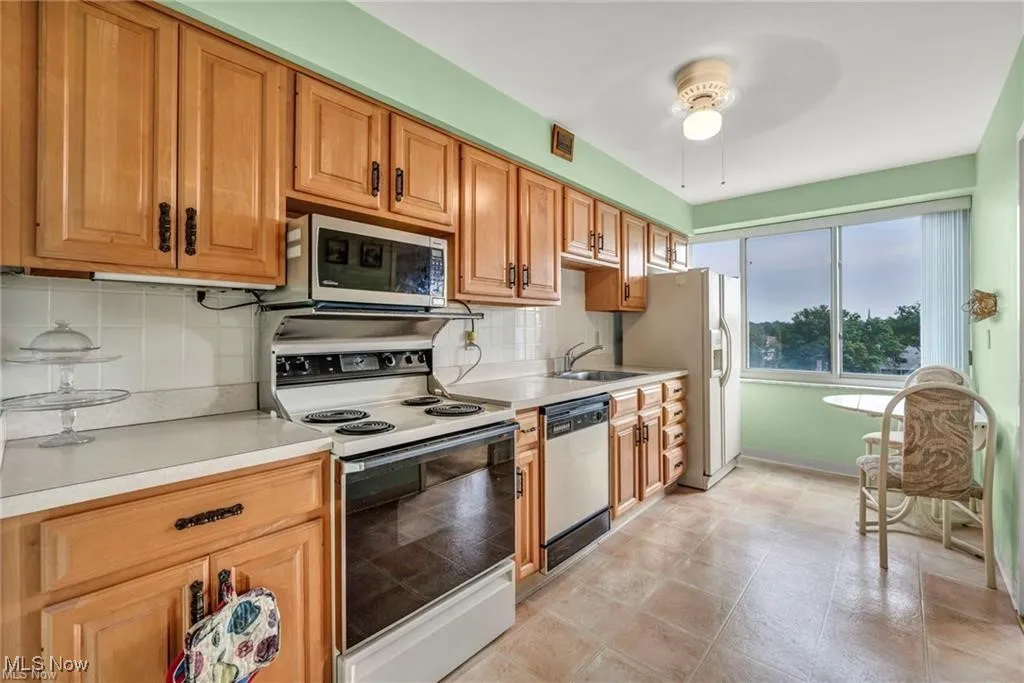 Kitchen with tasteful backsplash, light countertops, a ceiling fan, and brown cabinets