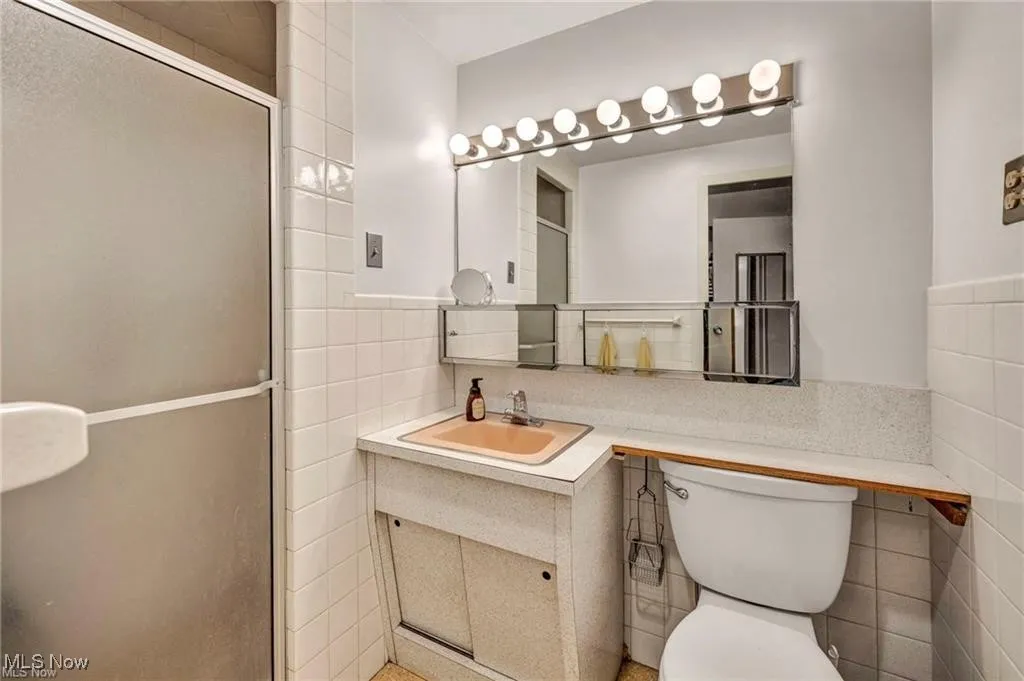 Bathroom with tile walls, vanity, and a wainscoted wall