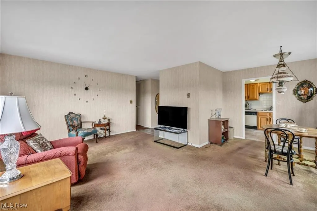 Living area featuring wallpapered walls and light colored carpet