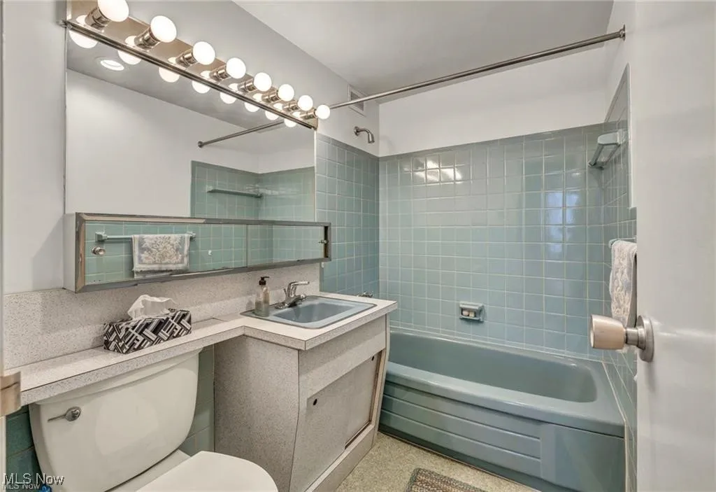 Full bathroom with shower / washtub combination, vanity, and tasteful backsplash