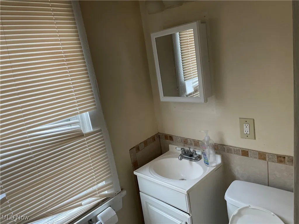 Bathroom featuring toile, tile walls, and vanity