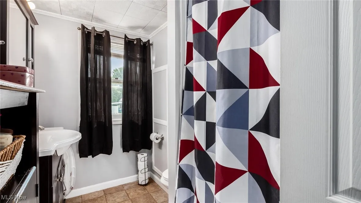 Full bath featuring ornamental molding and a shower with shower curtain