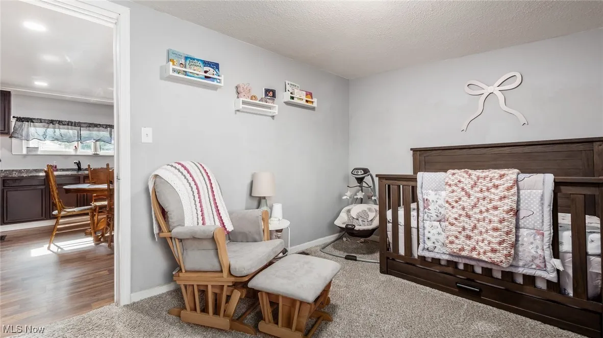 Carpeted bedroom featuring a crib and baseboards