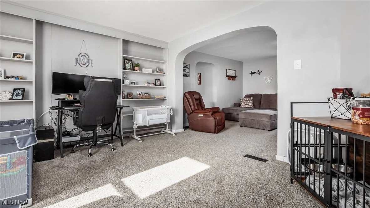 Carpeted home office with arched walkways and baseboards